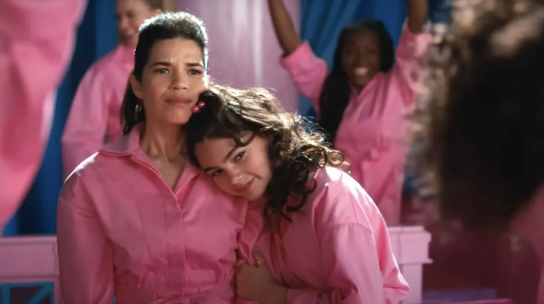 A mother sits with her daughter next her, both women are in pink jumpsuits